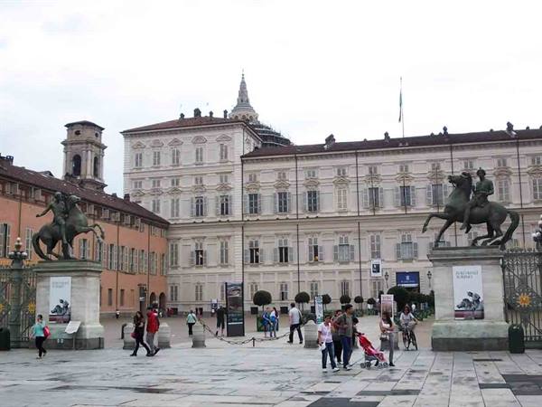 People strolling among the equestrian statues of Piazza Castello in Turin