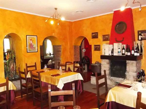 Trattoria dining room with ochre walls, set tables and stone fireplace