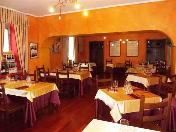 Restaurant dining room with set tables, yellow tablecloths, orange walls and warm lighting
