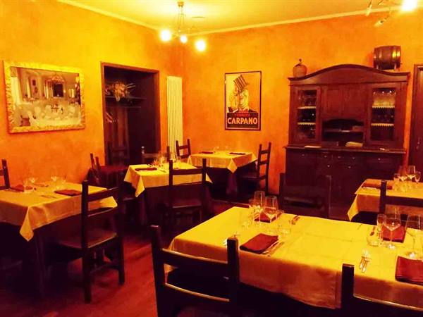 Restaurant dining room with set tables, yellow tablecloths, Carpano poster and wooden cabinet