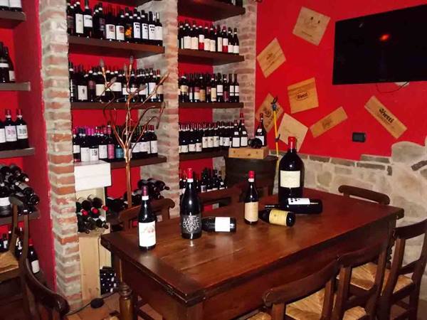 Wine bottles on wooden table and brick shelves against a red wall