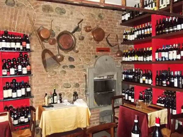 Wine cellar restaurant with red shelves of bottles, copper pans and stone oven