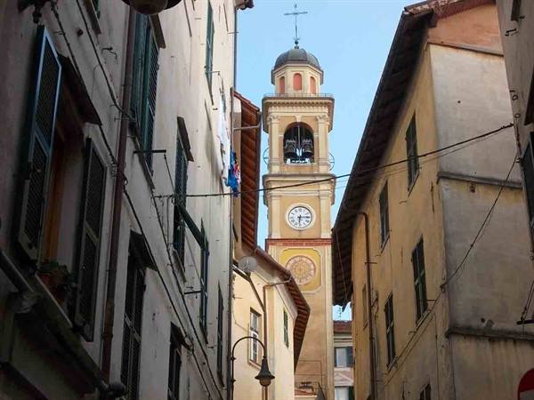 Bell tower with clock between ochre houses and green shutters