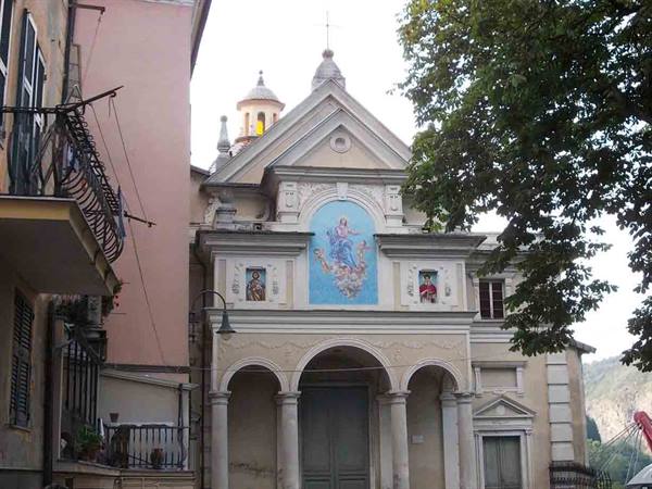 Baroque church with blue facade fresco, arches and bell tower among trees