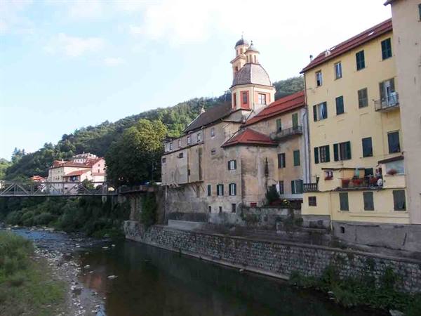 River with colorful houses and domed church, metal bridge on the left
