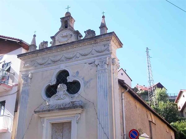 Baroque chapel facade with quatrefoil window, light plaster, blue sky