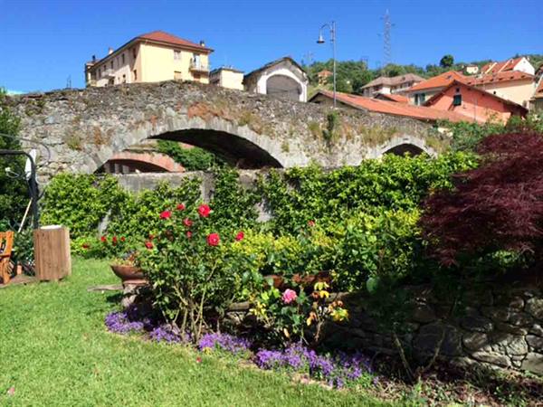Old stone bridge with arches above a blooming rose garden