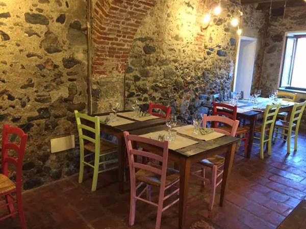 Rustic dining room with stone walls, set tables and colorful chairs