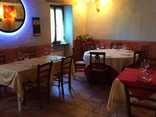 Trattoria dining room with set tables, colored tablecloths, wooden chairs and warm light