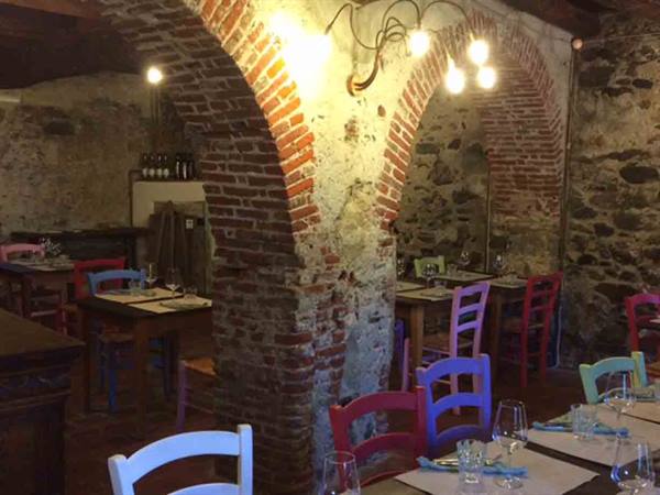 Rustic trattoria with brick vaults, colorful chairs and set tables under warm lights