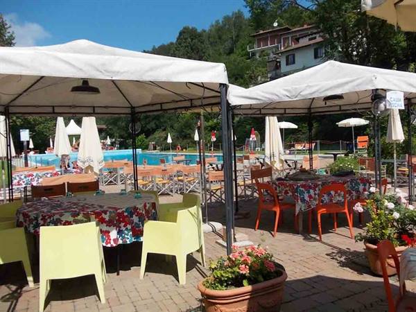 Tables with floral tablecloths under white gazebos beside the pool