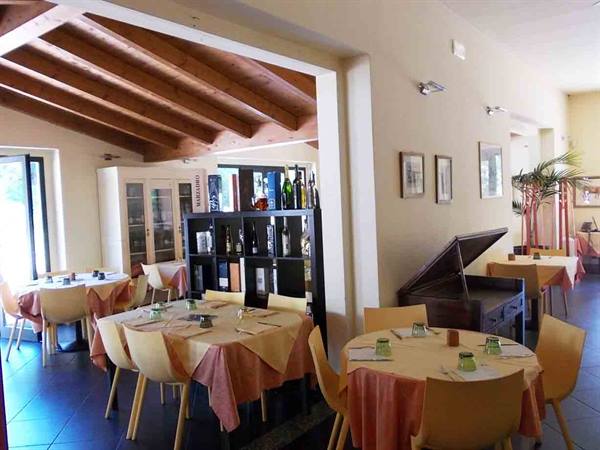 Restaurant dining room with set tables, pink tablecloths, yellow chairs and wooden beams