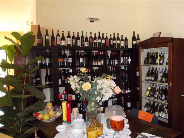 Table with fresh flowers and wine bottles on wooden shelves