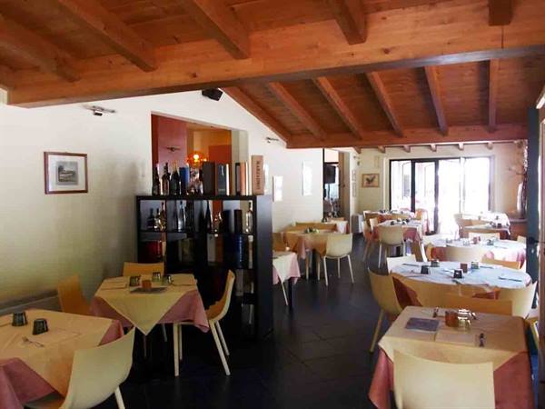 Restaurant dining room with set tables, white chairs and wooden beam ceiling