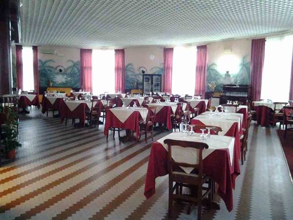 Empty dining room with set tables, white and red tablecloths, frescoed walls