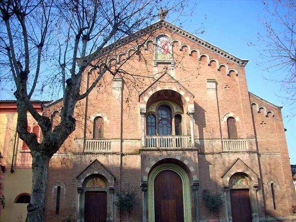 Brick church with decorated facade and bare tree, blue sky