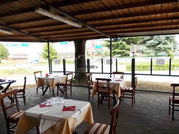 Wooden covered terrace with set tables, yellow tablecloths and a tree in the middle