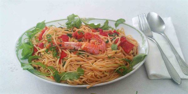 Plate of spaghetti with tomato, prawn and fresh arugula