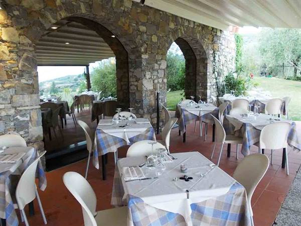 Restaurant terrace with set tables, stone walls, arches and white chairs