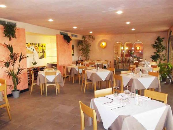 Restaurant dining room with white-clothed tables, pink walls and plants