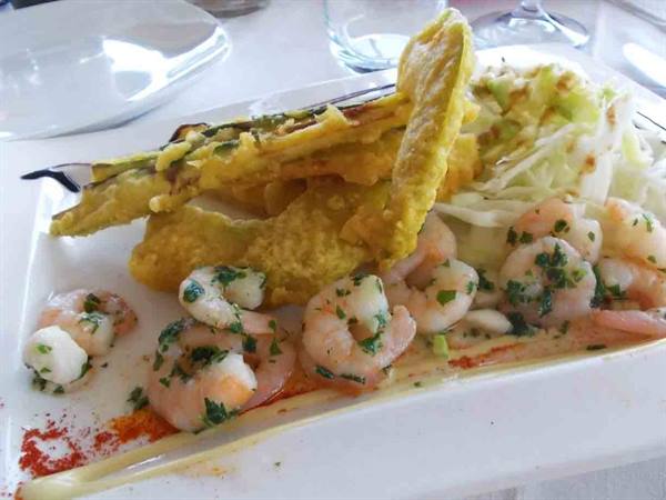 Herbed shrimp with crispy fried fish and shredded salad on white plate