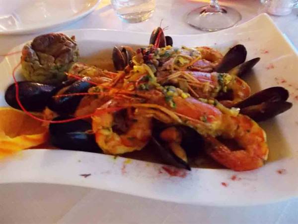 Prawns and mussels in sauce served on white plate in restaurant