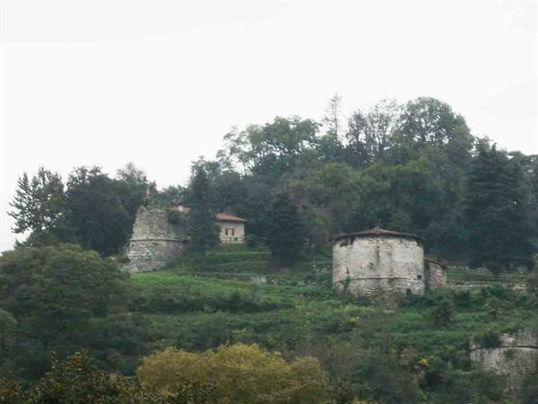 Old round stone towers on a green hillside in Bergamo