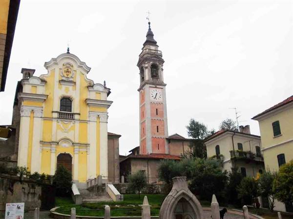 Yellow baroque church with red clock bell tower under grey sky