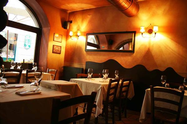 Trattoria dining room with set tables, ochre walls, warm wall lamps