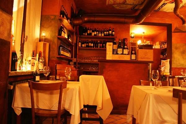 Trattoria dining room with white tablecloths and shelves of wine bottles