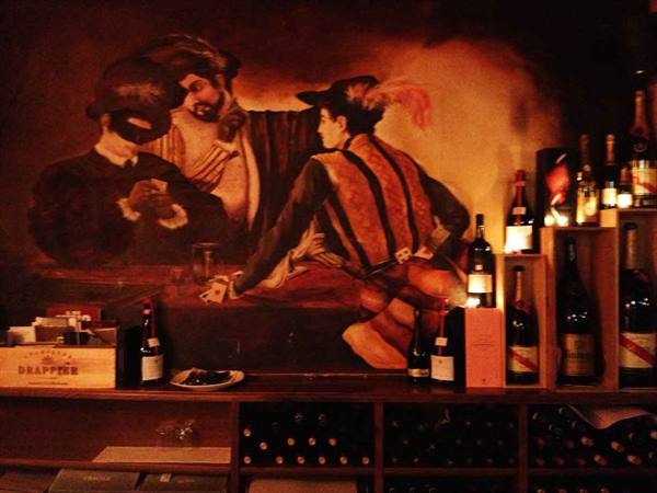 Venetian gambling mural with masked figures, wine bottles on display