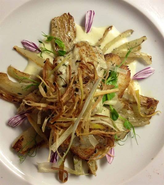 Gourmet dish with roasted artichokes, crispy shards, cream and purple flowers