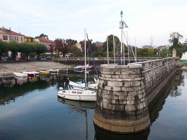 Sailboats moored beside a round stone pier with beacon