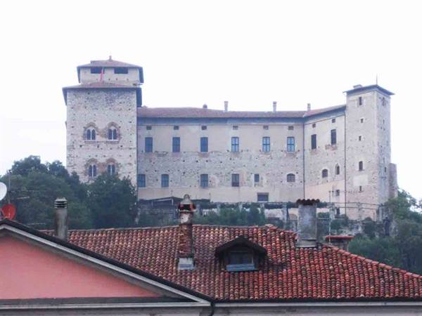 Stone castle with towers above red tiled roofs, grey light