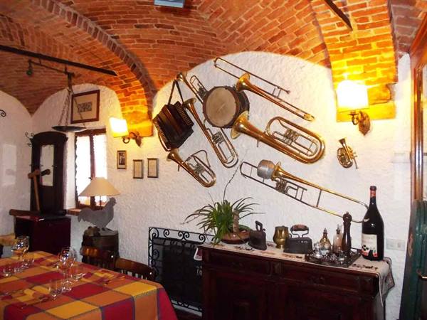 Trattoria dining room with brick vault and brass instruments hanging on white wall
