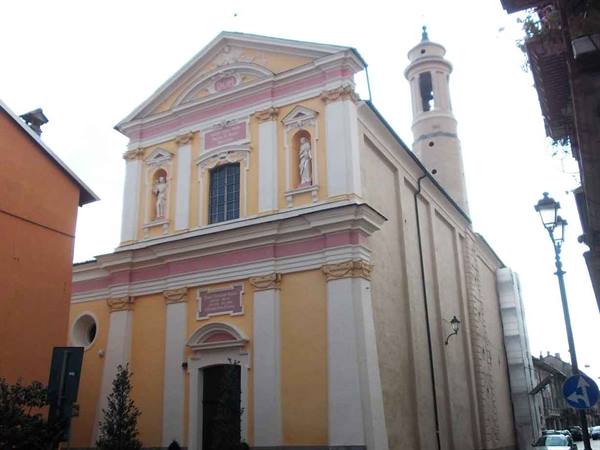 Yellow and pink church with statues in niches and white bell tower