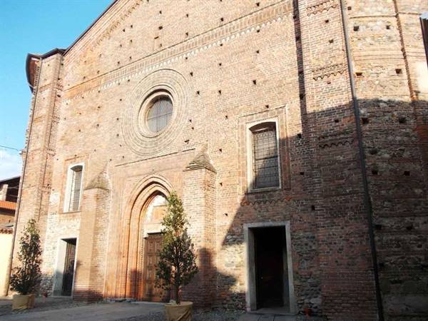 Brick facade of a medieval church with rose window and Gothic portal in morning light