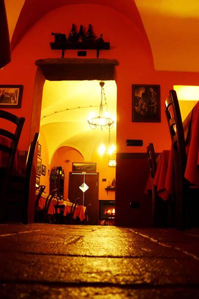 Trattoria dining room with orange vaulted ceilings, wrought-iron chandelier and brick floor