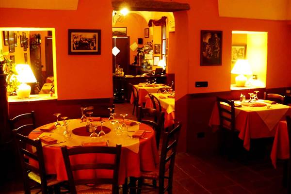Trattoria dining room with set tables, orange tablecloths and lit lamps
