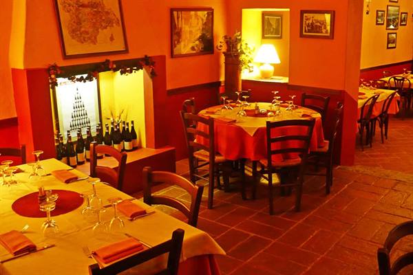 Trattoria dining room with set tables, red tablecloths and wine bottles