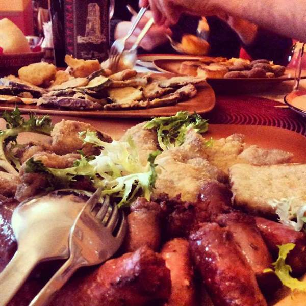 Table laden with sausages, fried food and bread, silver fork and spoon