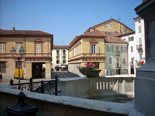Marble fountain square with pink flowers, yellow buildings and iron lampposts