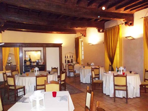 Dining room with white-clothed tables, wooden ceiling beams and yellow curtains