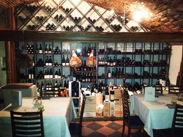 Restaurant wine cellar with bottles on brick shelves, hanging hams