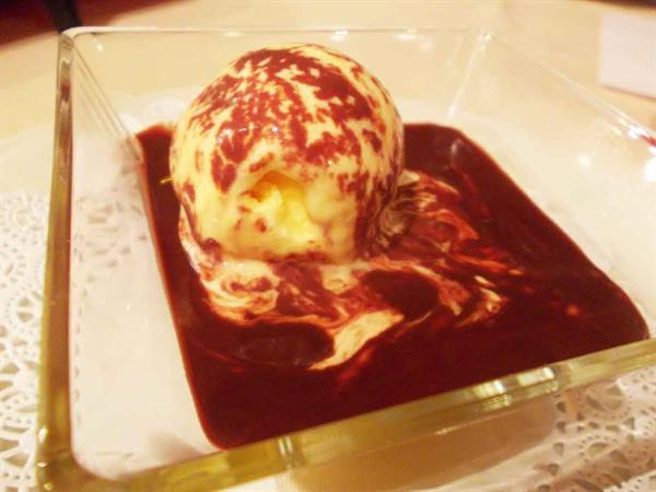 Vanilla ice cream scoop with chocolate sauce on a glass plate