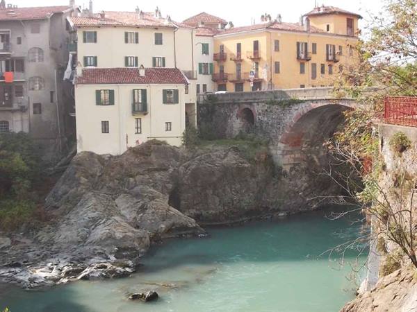 Old stone bridge over turquoise river among colorful houses