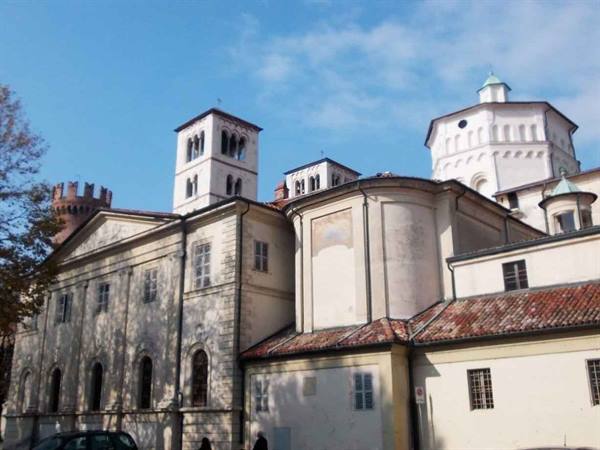 Santuario della Consolata in Turin, white facade, bell towers and tiled roofs under blue sky