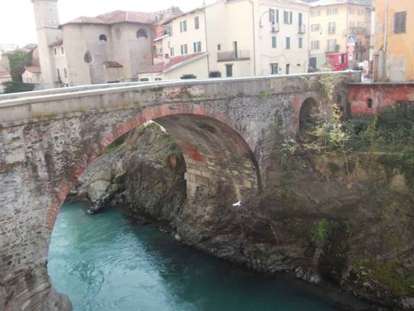 Ancient stone bridge over turquoise river, colorful houses of the old town