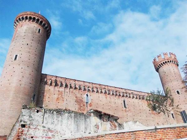 Brick crenellated towers of Ivrea castle under a bright blue sky