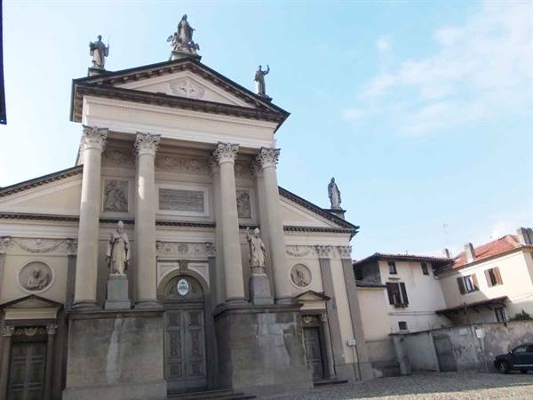 Neoclassical facade of Ivrea Cathedral with columns and statues in morning light